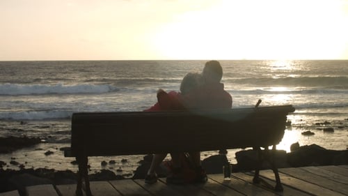 Middle-Aged Couple Hugging on a Bench with a Sea View in the Background