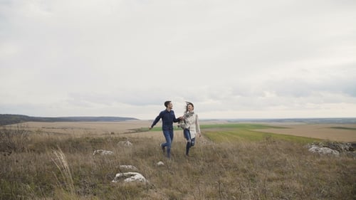 Lovely Couple Running on the Rock and Man Twisting Girl in Windy Day