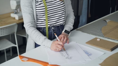 Young Woman Fashion Designer Drawing in Studio