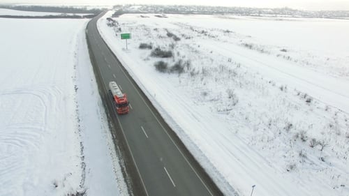 LKW fährt Winterstraße im verschneiten Feld