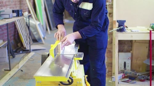 Carpenter Using Electric Planer in Workshop