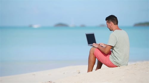 Junger Mann mit Tablet-Computer im tropischen Strandurlaub