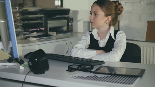 Hübsches Schulmädchen denkt am Arbeitsplatz im Büro.