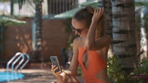Girl Straightens Haircut Holds Phone by Home Pool