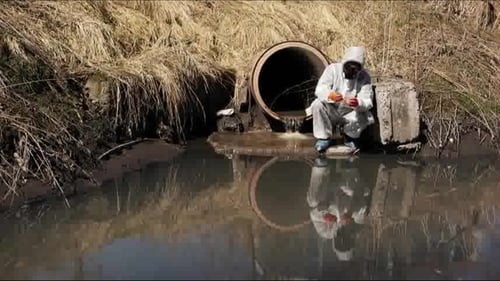 Scientist in Hazmat Suit Inspecting Water Sample