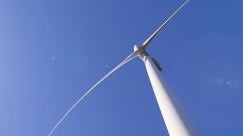 Les lames blanches du moulin à vent tournent dans les airs contre le ciel bleu