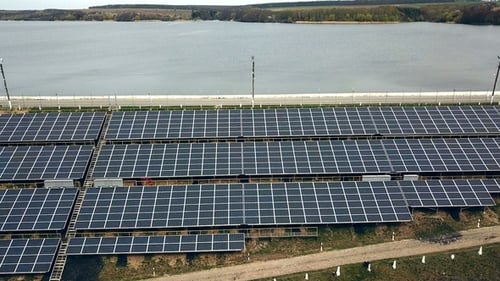Sonnenkollektoren nahe dem Fluss. Kraftwerk. Blaue Solarmodule. Alternative Stromquelle