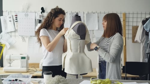 Kreative Modedesigner heften ausgeschnittene Stoffstücke an die Schaufensterpuppe