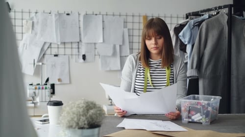 Fashion Designer Reviews Sketches in Bright Studio