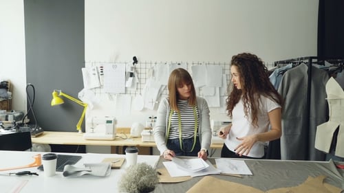 Young Fashion Designing Entrepreneurs Are Discussing Sketches of New Clothes Collection in Their