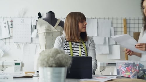 Owner of Tailoring Studio Is Working with Laptop in Workplace While Her Designer Is Coming To Her