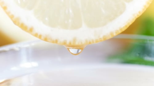 Close Up of Lemon Slice Dripping Into Glass