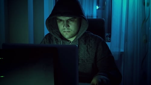 Hooded Hacker Uses Computer in Dark Room