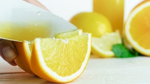Aufnahmen vom Handschneiden von saftigen Orangen auf Scheiben mit einem großen Messer