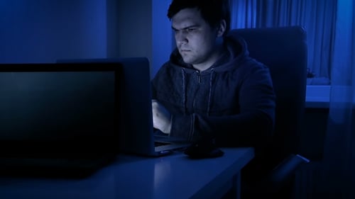 Aufnahmen eines jungen Mannes mit Hoodie und Brille bei der Arbeit am Computer