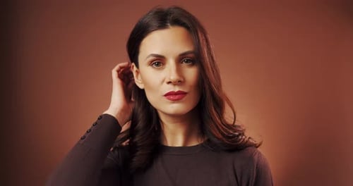 Beautiful Woman Poses in Studio on Brown Background