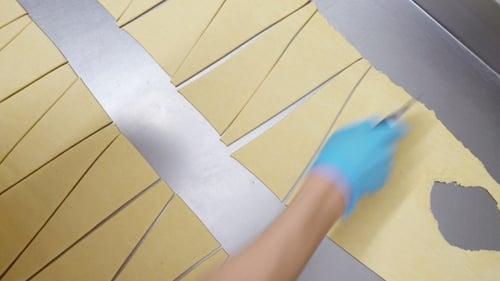 Traditional Italian Bakery. A Female Baker Cuts Dough for Baking Croissants