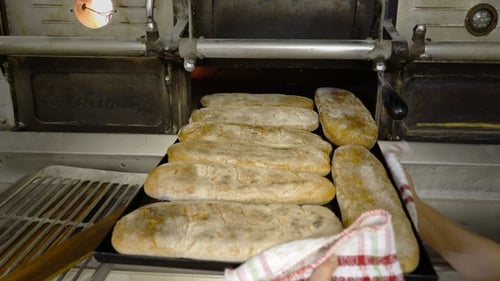 Traditional Italian Bakery. A Female Baker Takes Hot Bread Out of the Oven