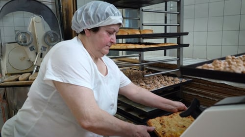 Traditional Italian Bakery. A Female Baker Cuts a Big Pie Into Pieces