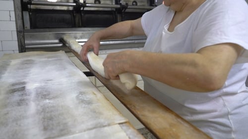 Traditional Italian Bakery. A Woman Baker Prepares Bread for Baking
