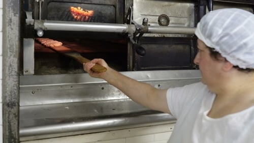 Traditional Italian Bakery. The Woman Baker Puts the Bread in the Oven for Baking