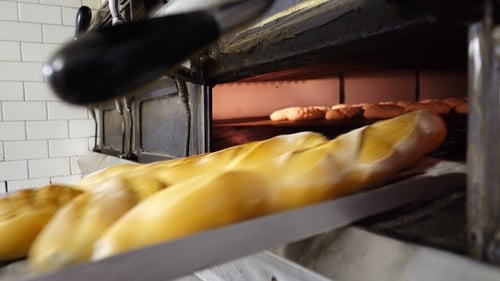 Bäckerin holt heißes Brot aus dem Ofen