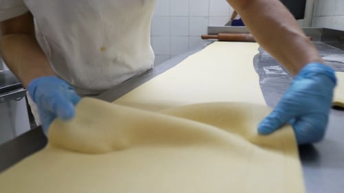 Baker Rolling and Cutting Dough in Commercial Kitchen