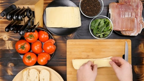 Person Preparing Sandwich with Cheese, Tomato, Prosciutto
