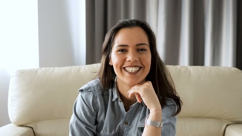 Smiling Woman Relaxing on Cream Colored Sofa