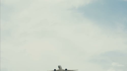 Airplane Flying High Above in Cloudy Sky