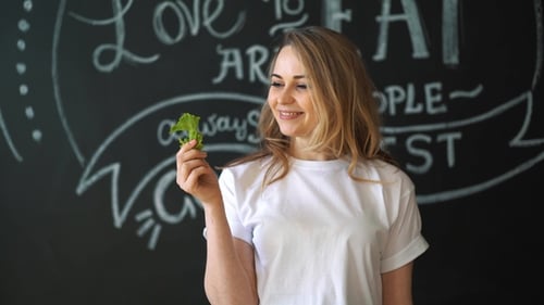 Healtcare, Food and Diet Concept - Smiling Woman Biting Piece of Celery or Green Salad
