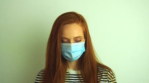 Woman with Mask Puts on Yellow Cleaning Gloves