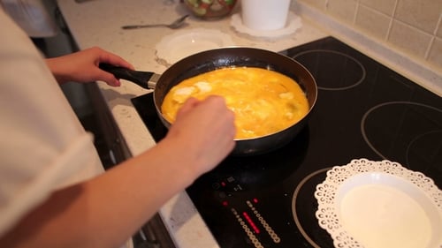Person Mixes Eggs in Pan on Stovetop