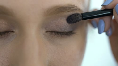 Die Visagistin malt die Augen eines jungen Mädchens