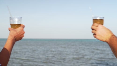 Young Family Couple Sunbathing and Drinking Colored Cocktail at Tropical Beach. Lovers on Honeymoon