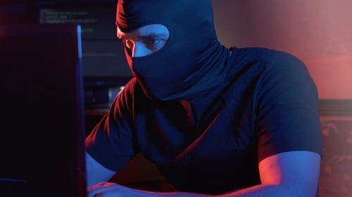 Masked Person Typing on Computer in the Dark
