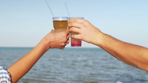 Young Family Couple Sunbathing and Drinking Colored Cocktail at Tropical Beach. Lovers on Honeymoon