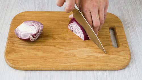 Adult Cutting Red Onion on Wood Cutting Board