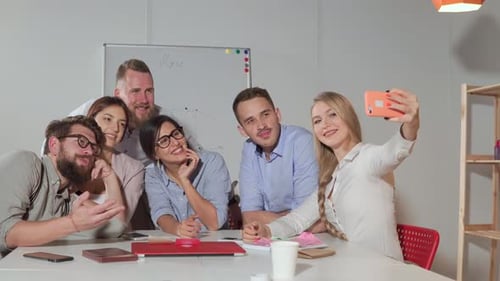 Blonde Woman Is Taking Selfie with Her Colleagues in Office Using Smartphones