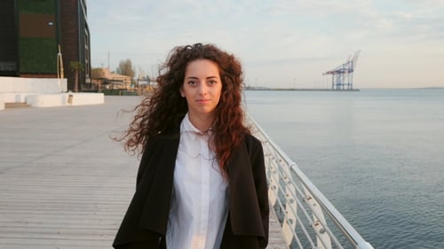 Beautiful Girl with Curly Long Hair Walking Towards the Camera on Sunny Spring Sea Beach. Young