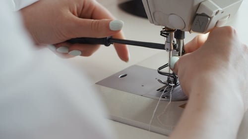 Mains féminines travaillant sur une machine à coudre. Tailleur répare une machine à coudre