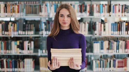 Smiling Female Student Hold Books Standing Before the Shelves in the Library