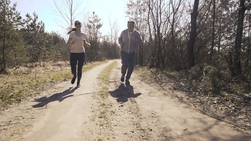 Happy Father and Daughter Jogging in the Early Forest.