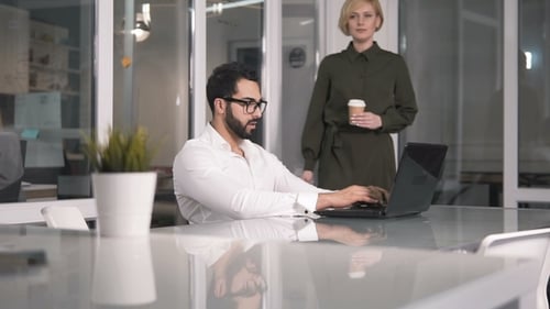 Man Works at Laptop as Woman Approaches