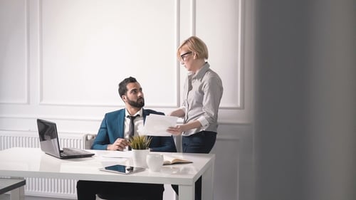 Man and Woman Discussing Documents in Office
