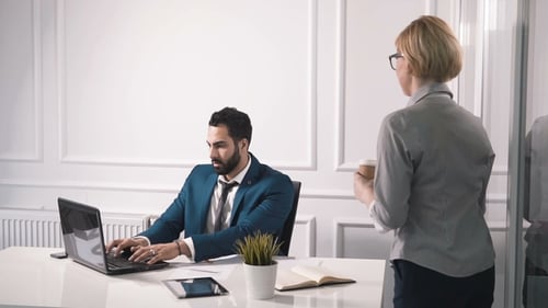 Woman Brings Coffee to Man Working at Desk