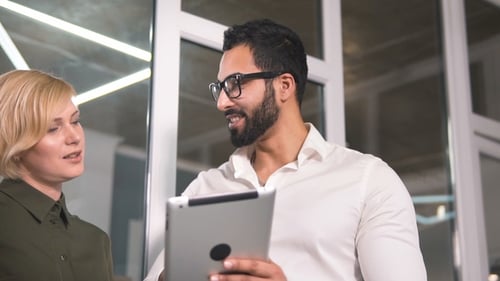 Man and Woman Work on Tablet in Office