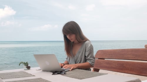 Young Woman Works on Laptop in Outdoor Cafe