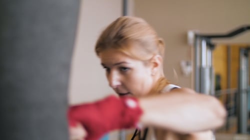 Junge Frau trainiert mit einem Boxsack in einem Boxclub.