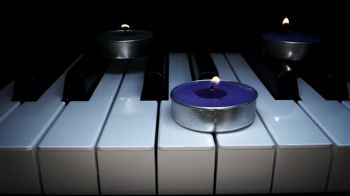 Candles Burning on Piano Keyboard at Night